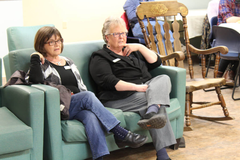 Two people listening to a speaker.