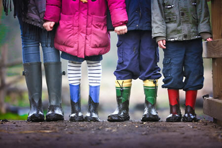 Children wearing warm coats and rainboots.